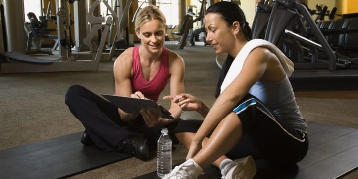 female trainer showing female client something on clipboard