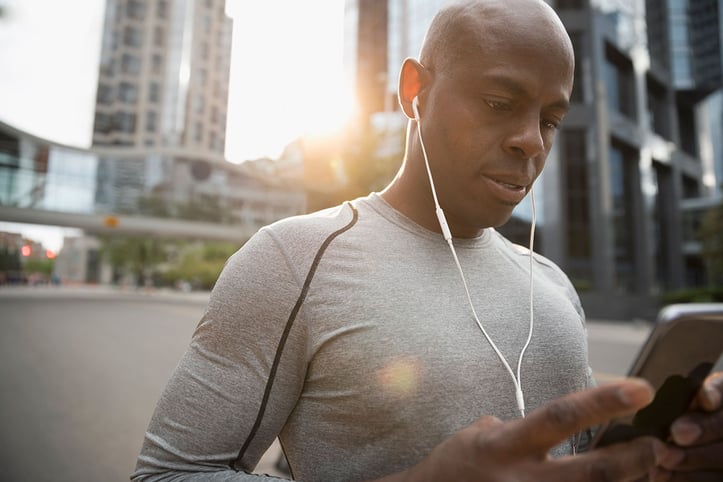 Man with his headphones in and looking at phone