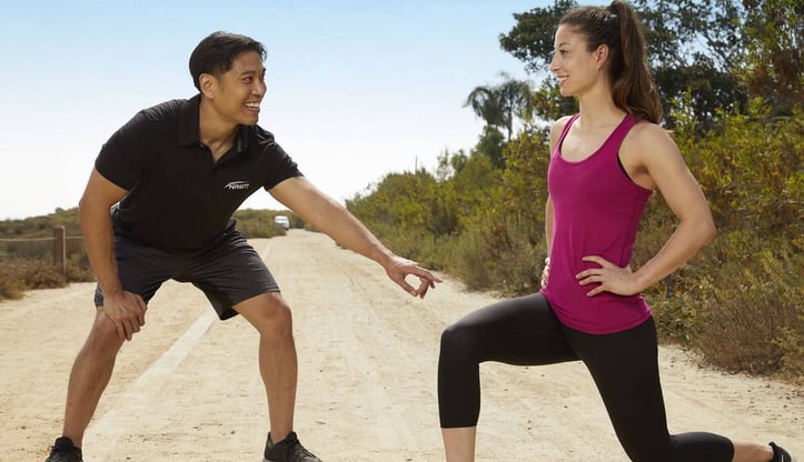 Male NASM trainer assisting female client in front lunge