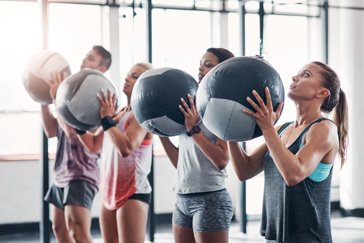 group fitness class holding weighted smash balls