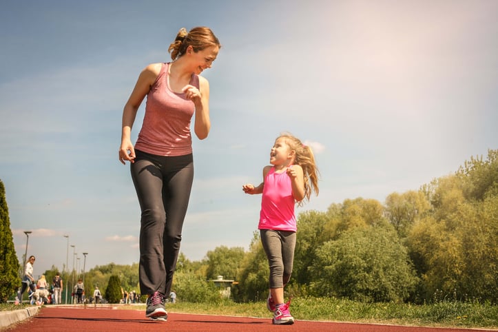 Mother running with her young daughter outside on a track