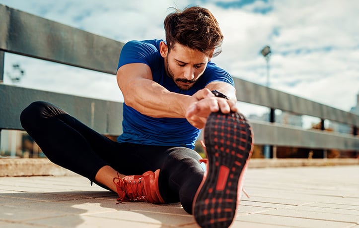 A man doing active recovery stretches outside