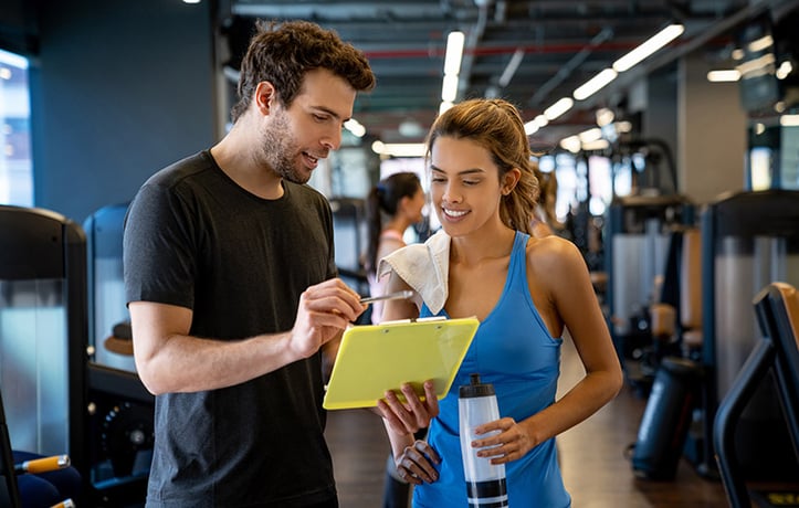 trainer with clipboard going over workout with client