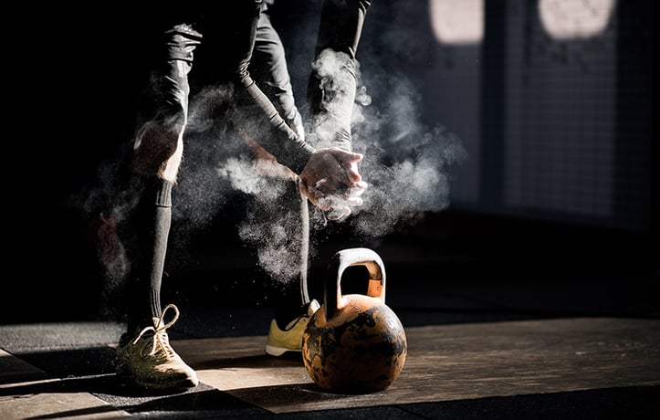 a man with chalk on his hands about to do a kettlebell workout