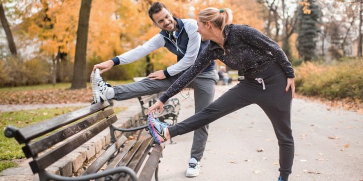 2 trainers doing flexibility training on a park bench