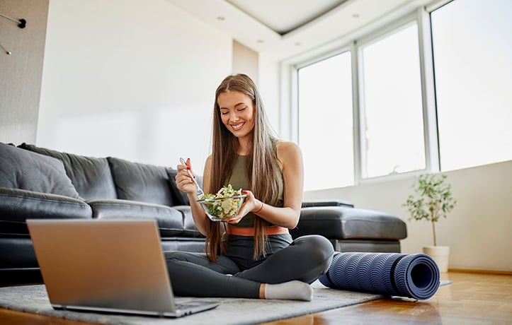 nutrition coach eating healthy greens in front of laptop