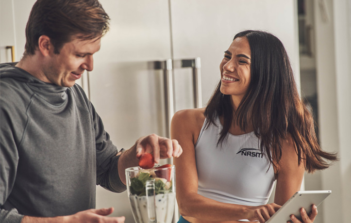 A wellness and nutrition coach making a smoothie in a kitchen