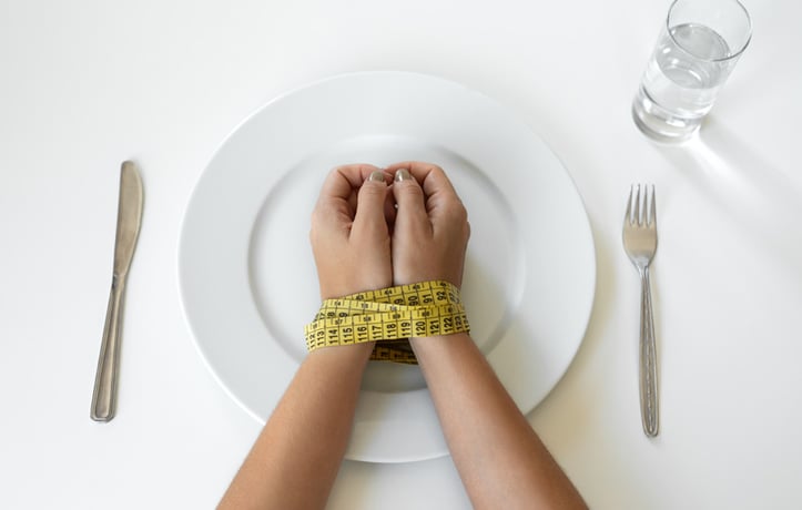 A ladies hands tied with a measuring tape on a plate