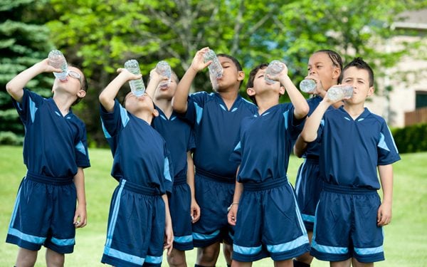 Group of kid soccer players drinking out of water bottles