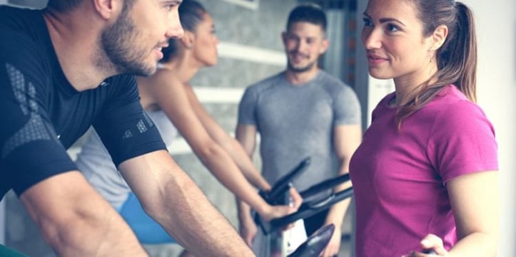 A Woman Talking to a Man on a Exercise Bike