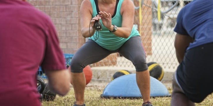 Woman doing squat outside with workout equipment around