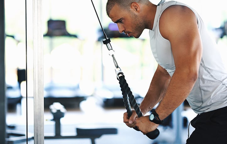 man doing a tricep pull-down on the cable machine