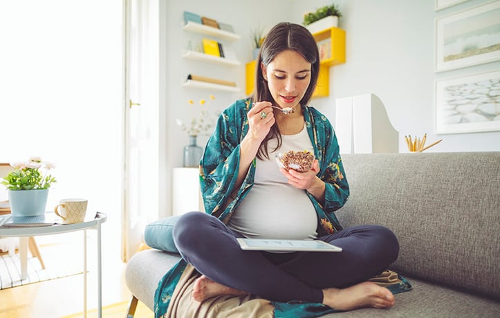 pregnant woman eating on her couch