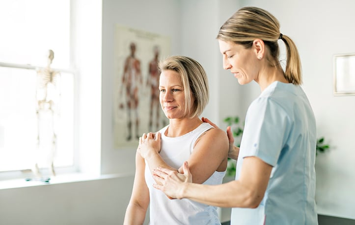 physiotherapist helping a woman's range of motion in shoulder