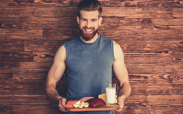 man smiling at camera holding a tray of healthy foods