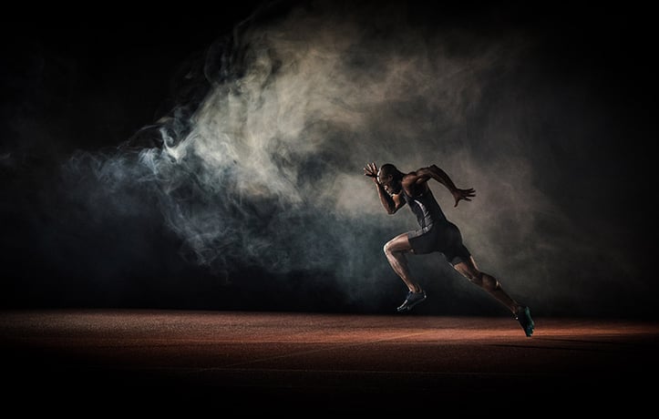 Athlete sprinting on track field in the dark