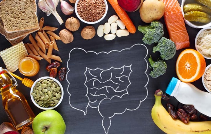 A table with mixed foods and a chalked drawling of a gut