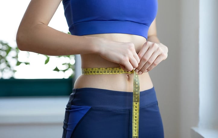 woman measuring her waist with flexible measuring tape