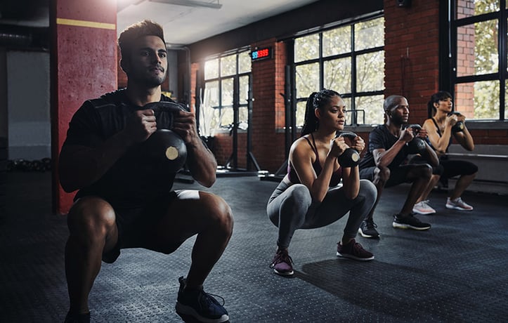 beginners doing kettlebell squats in a gym